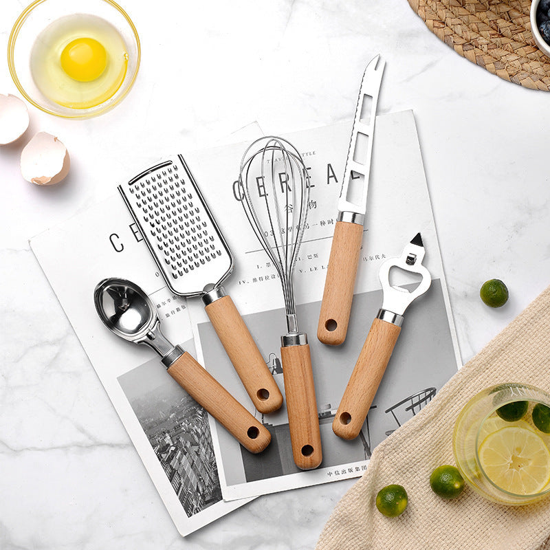 Ustensiles bois et inox disposés sur fond rustique pour cuisine chaleureuse